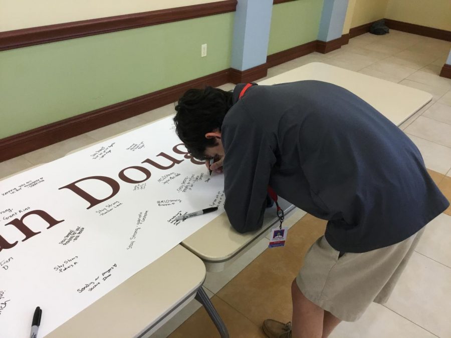 Student signs banner.